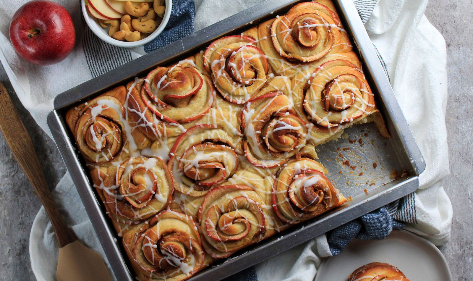 Freshly baked tray of Apple Cashew Butter Rolls with a golden, flaky exterior and apple slices peeking through making the rolls look like roses.