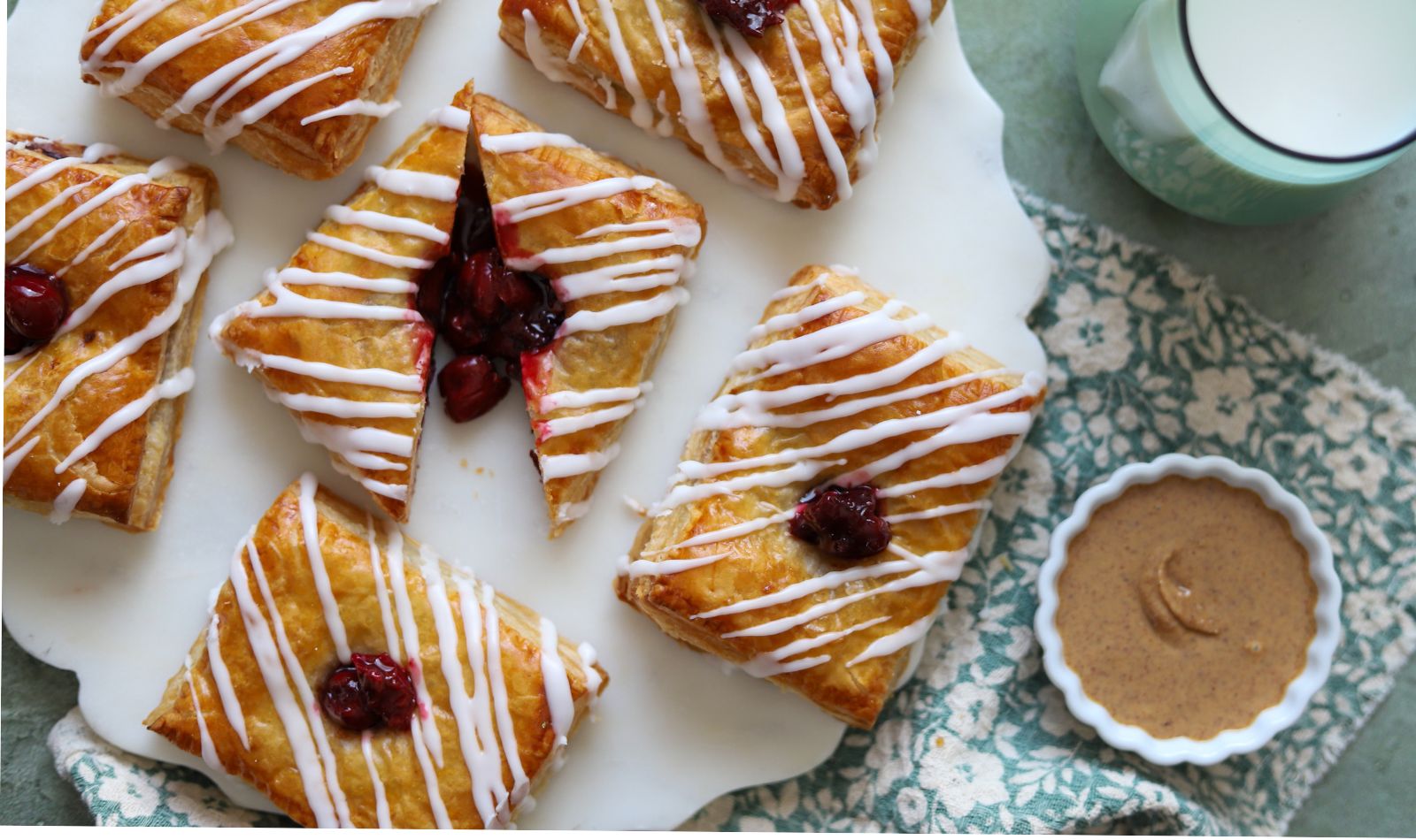 Cherry Almond Butter Strudels with a golden, flaky puff pastry exterior, filled with a sweet cherry-almond mixture and topped with a vanilla glaze.